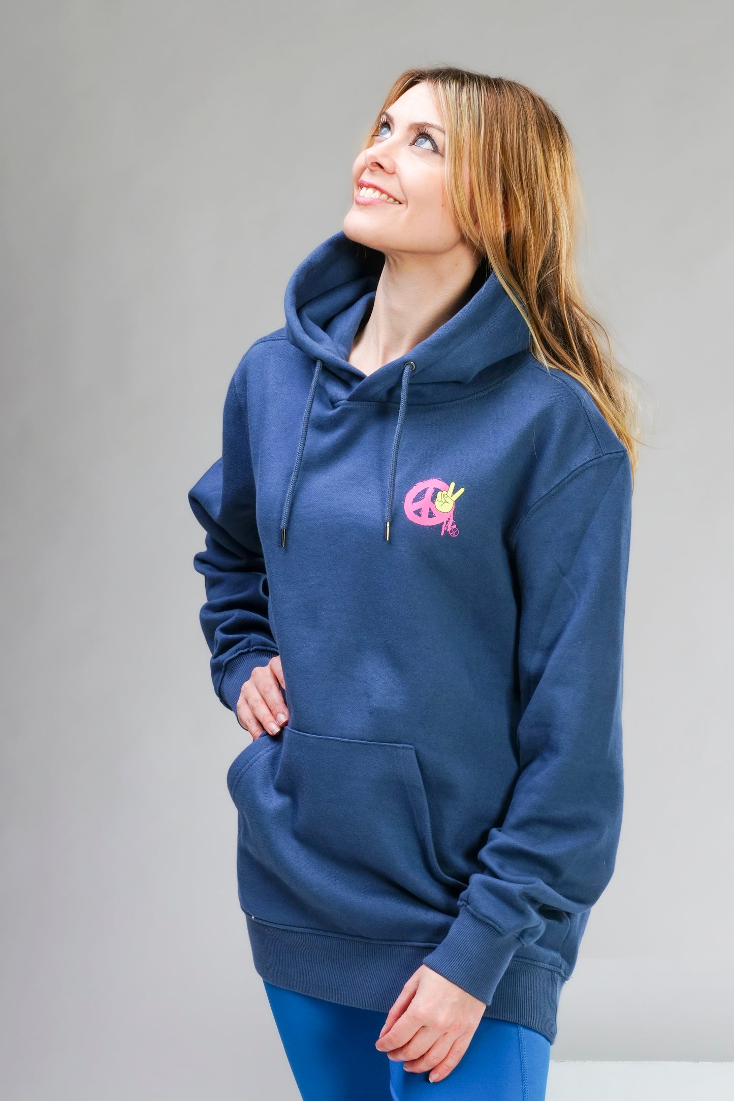 Damen Hoodie „Peace“ in Denimblau mit pinkem Print – kuschelig, fair produziert & im Unisex-Style. Model trägt Größe L.